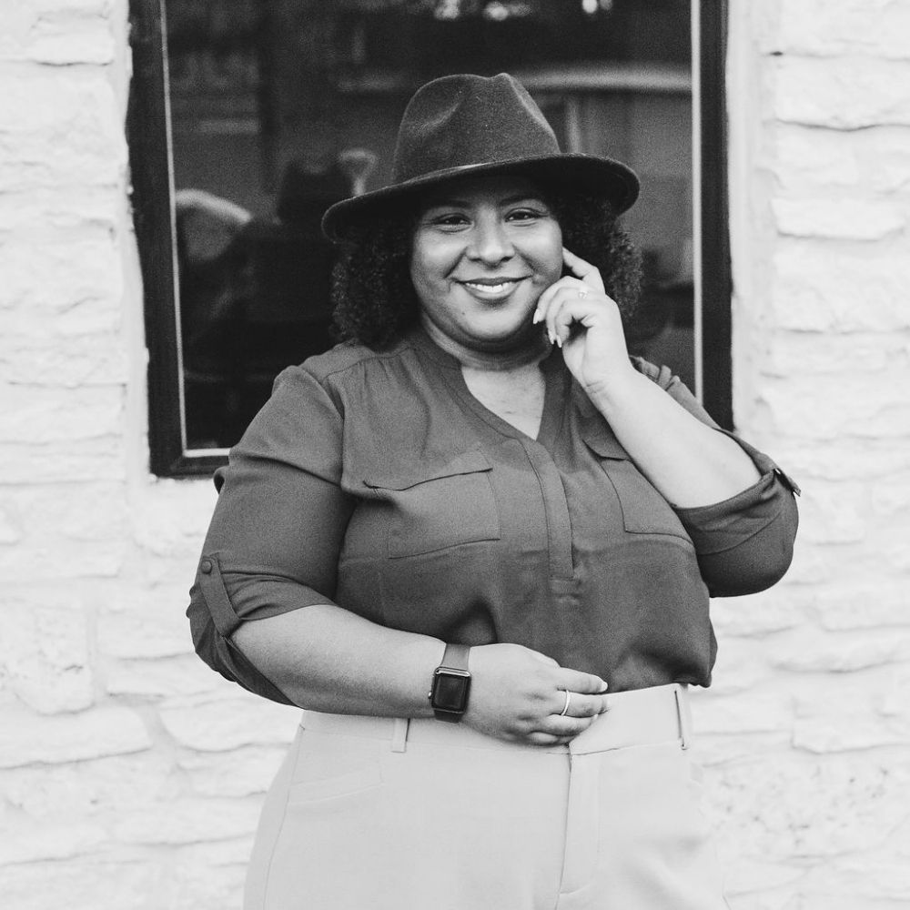 Woman standing in front of building wearing a hat