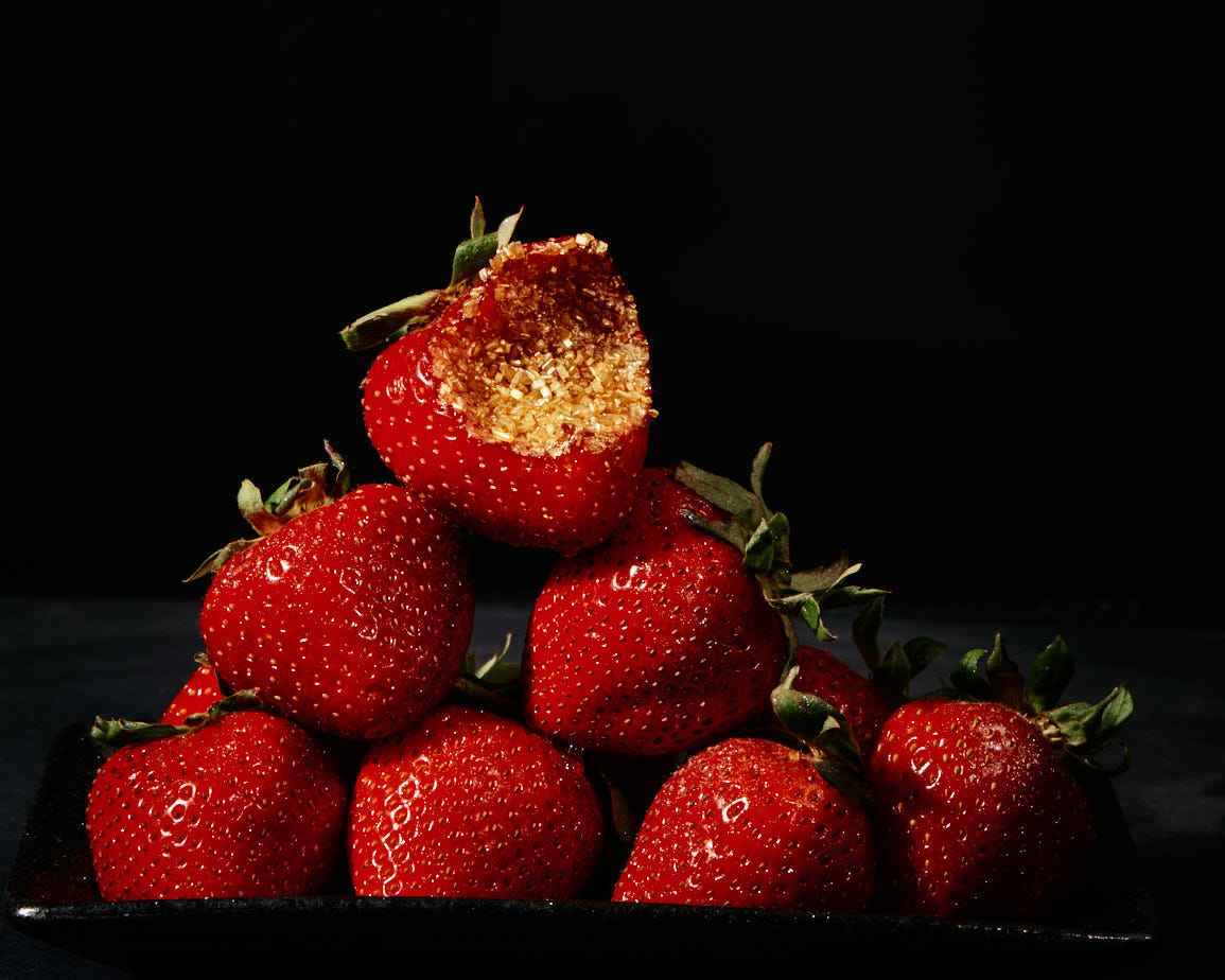 stack of red strawberries with the top bitten into with gold glitter