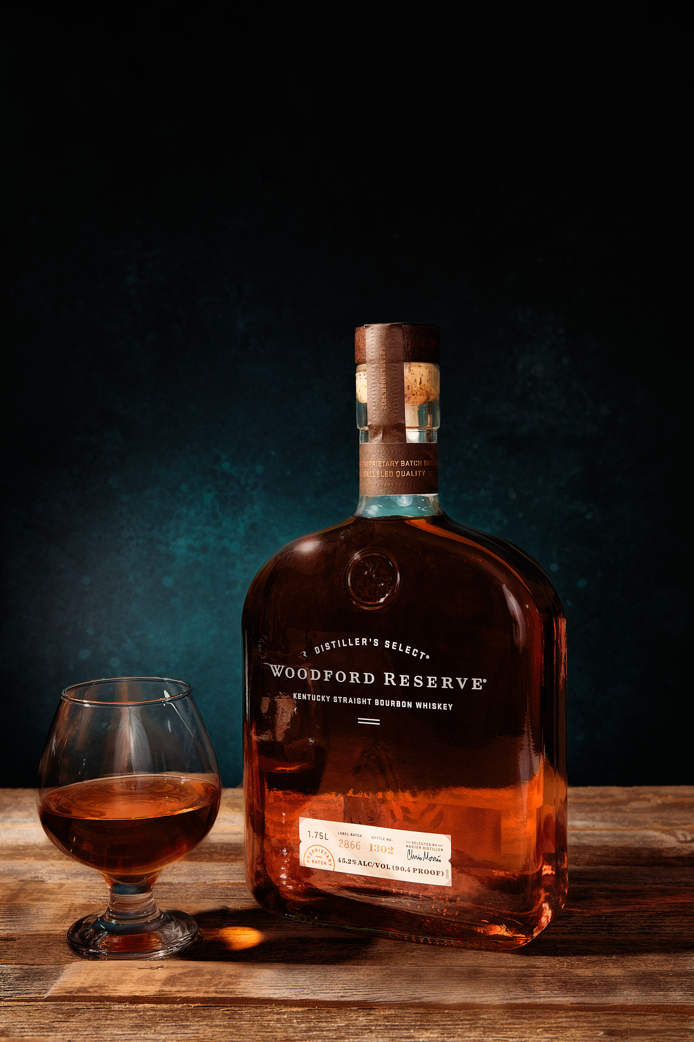 Bottle of Woodford Reserve Kentucky Straight Bourbon Whiskey with a glass of bourbon on a wooden table.