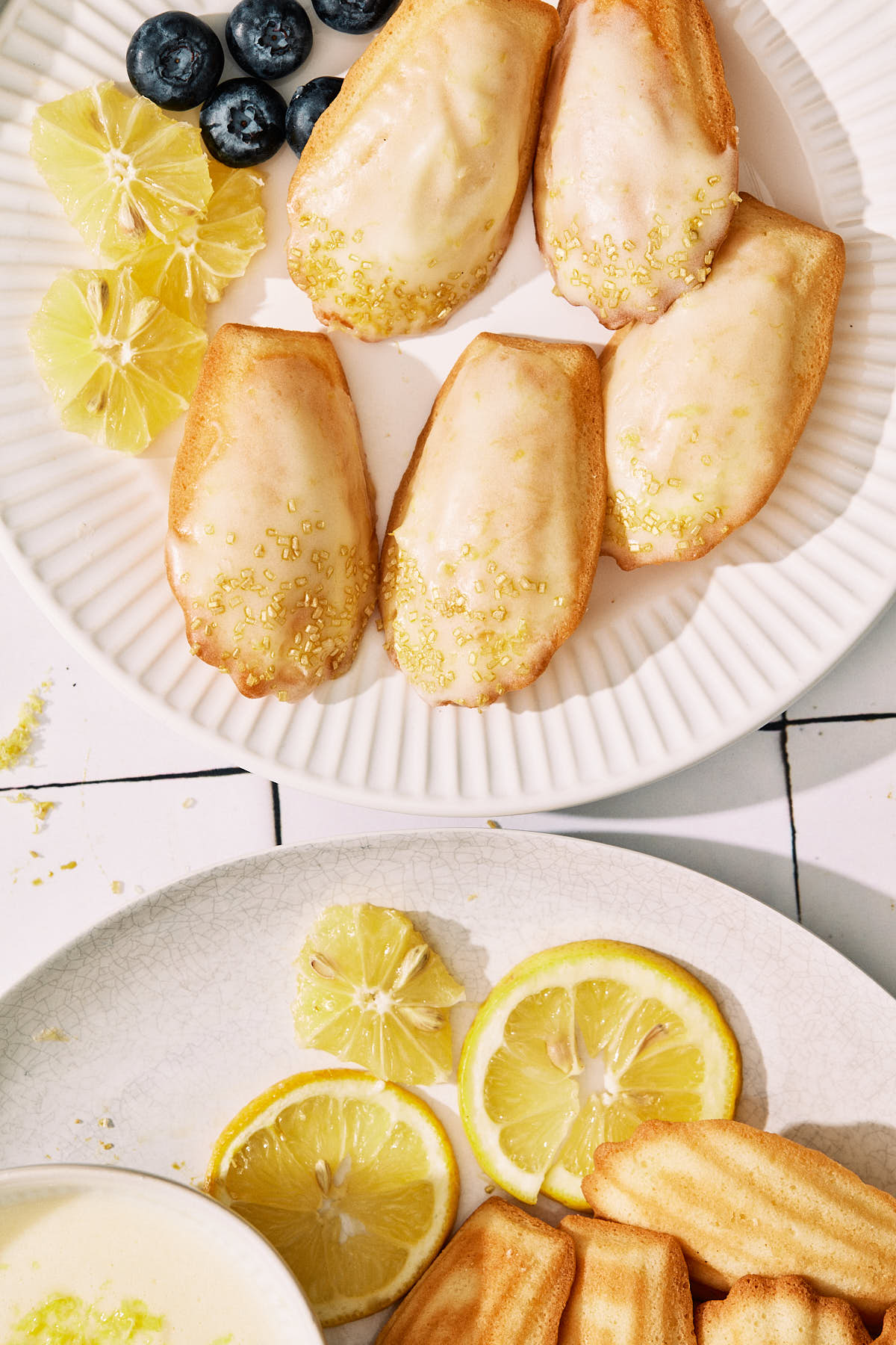 Lemon madeleines with lemon slices and blueberries on white plates