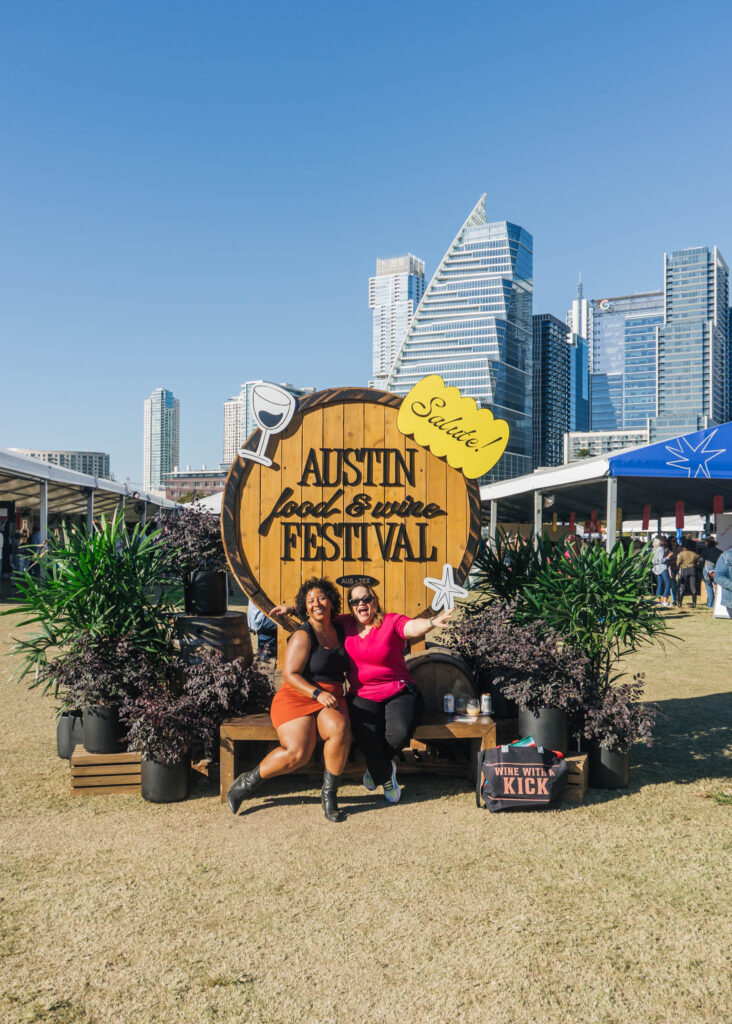 Friends posing at Austin Food & Wine Festival sign in downtown Austin