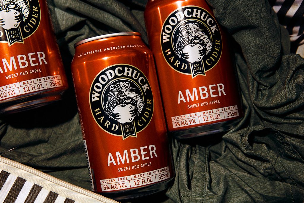 Woodchuck Cider cans styled with wicker basket and green fabric